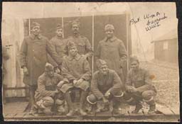 Photograph of Private William H. Furrowh with a group of soldiers in front of barracks during World War I. Writing in pen on photo misspells Furrowh's middle initial as "A." Writing on back of photograph reads "Somewhere in France/from Will."  