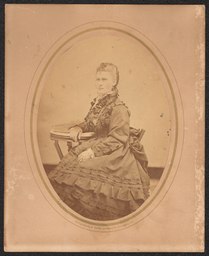 Enlarged portrait of a woman in a ruffled dress sitting and posed with a side table. From the studio of Wilmington photographer Emily Webb.