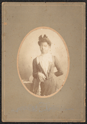 Photograph of a woman wearing glasses leaning on a chair. The photograph is from the waist up and is in a brown-gray board with an oval cut out for the image. Underneath the image is a metallic stamp that reads: "R.C. Holmes, State Street, Dover, Delaware".