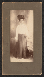 Photograph of a woman wearing a white shirt, dark skirt, and a large hat. The photograph is mounted on a dark brown board, Very faintly embossed under the photograph is "A.N. Sanborn 401 Market Street Wilmington, Del.".