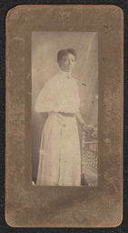 Photograph of a woman wearing a white lace dress standing next to a chair. Mounted on brown board. Embossed under the photograph is "A.N. Sanborn 404 Market Street, Wilmington, Del.".