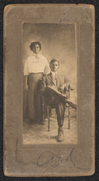 Photograph of a man and a woman mounted on gray board. The man is seated and the woman stands behind him with her hand on his shoulder. Embossed beneath the photograph is "A.N. Sanborn 404 Market Street Wilmington, Del.". There appears to be a crayon inscription as well, but it is unclear what it says.