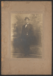 Photograph of a standing man wearing a three-piece suit, bowler hat, and bow tie in a brown decorated frame. The name and address are embossed on the lower right corner of the frame. It reads: "Royal Studios, 407 Market St., Wilmington, Del.".