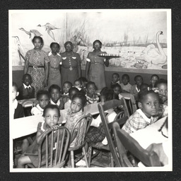 View of children and teachers during snack time at the Garrett Settlement House. During the Depression, settlement houses such as these provided families with food and shelter and acted as orphanages.