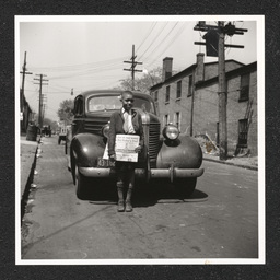 Newsboy, a boy poses in front of a car with Philadelphia Afro-American, March, 1941