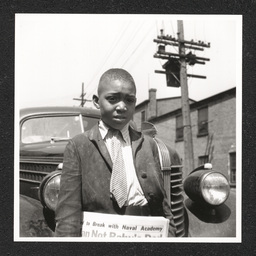 Newsboy, a boy poses in front of a car with Philadelphia Afro-American, March, 1941