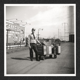 Pennsylvania Railroad Station, porter poses with luggage cart, 1938-40