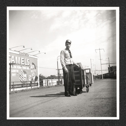 Pennsylvania Railroad Station, porter poses with luggage cart, 1938-40