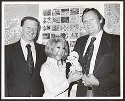 Shari Lewis and two men posing by Christmas seals, 1978