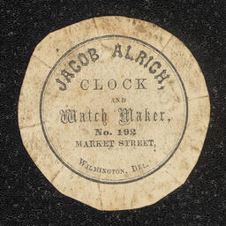 Off-white watch paper with printed inscription that reads, "Jacob Alrich, Clock and Watch Maker, No. 192 Market Street, Wilmington, Del."