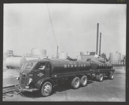 Photograph showing company tank trucks at refinery.