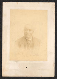 Photograph of a man with a mustache wearing a suit in a white card frame. The name and address of the photography studio are embossed along the bottom edge of the card. It reads: "Cummings Wilmington, Del.".