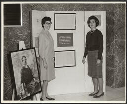 Two women standing by historical Christmas seals and Emily Bissell's portrait, 1965