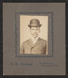Photograph of a man wearing a bowler hat mounted on a dark gray board. Printed below the photograph is "R. G. Holland 311 Market St., Wilmington, Del.".