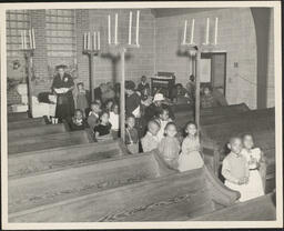 Children walking down chapel aisle with teachers, 1955