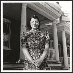 Exterior view of African American YWCA at 1301 Tatnall Street in Wilmington, Delaware. Mrs. Alberta Russell Williams, a YWCA employee, poses near front steps.