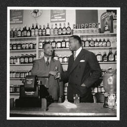 Johnson's Liquor Store 528 Lombard St., Charles Johnson shakes hands with man, 1940